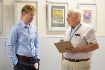 Two men stood chatting over a clipboard